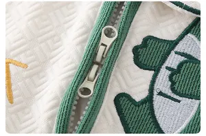 Detail of newborn cotton romper featuring a dual-way zipper and dinosaur embroidery