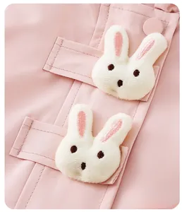 Close-up of pink toddler jacket featuring two cute white plush bunny decorations