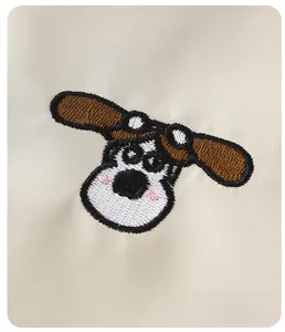 Close-up of cute cartoon dog embroidery on premium beige twill fabric for kids outerwear