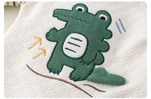 Close-up of baby romper featuring a 3D cartoon crocodile embroidery on quilted cotton fabric