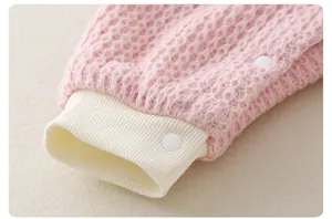 Detail of pink waffle knit baby romper with ribbed cuffs and secure snap fasteners