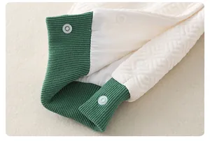 Macro shot of quilted cotton baby romper with white snap buttons and green ribbed edge