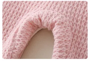 Detailed macro view of soft pink knitted baby romper fabric with delicate texture