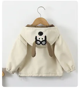 Detail of children's hooded jacket featuring cute cartoon dog ears on off-white fabric