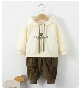 Detail of a kids beige cotton hoodie and brown corduroy cargo pants in a soft home setting