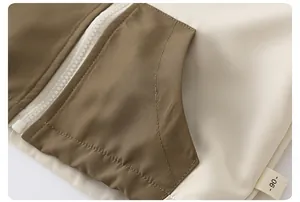 Detail of child jacket showing olive and cream fabric with smooth white zipper