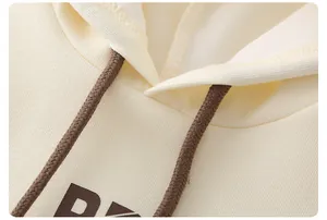 Detail of cream kids hoodie with knit texture, dark drawstrings and chest print