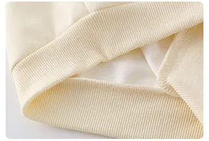 Macro shot of rib-knit cuffs on cream-colored cotton vest showing high-quality stitching