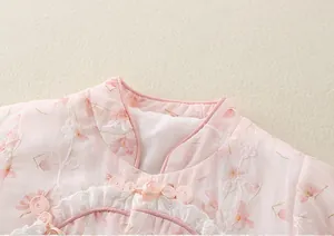 Détail d'un barboteuse rose pour bébé avec col mandarin chinois, nœuds et broderie dentelle