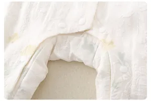Detailed macro view of white baby romper with floral jacquard fabric and resin snap buttons