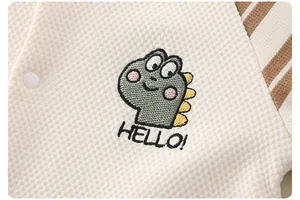 Detailed macro view of waffle cotton baby romper with cute dinosaur embroidery and HELLO text