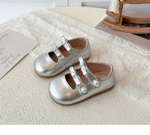 Détail de chaussures argentées pour filles avec doubles nœuds et perles nacrées