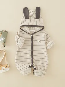 Striped baby bodysuit with rabbit ear hood and smile patch on soft textured background
