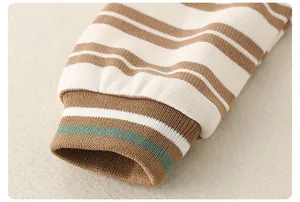 Close-up of striped baby sleepsuit showing detailed brown ribbed cuffs and soft cotton knit fabric