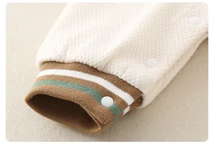 Detail of baby cotton quilted romper showing ribbed striped cuffs and snap buttons