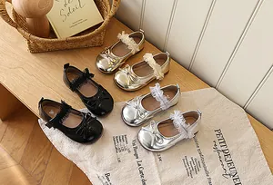 Three pairs of girls' bow Mary Jane shoes in gold, silver, and black on a wooden table