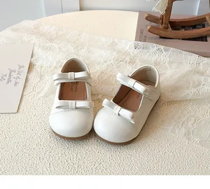 Detail view of cream white Mary Jane shoes for girls featuring double bows and rubber soles