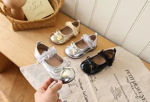 Three colors of Mary Jane shoes with delicate lace straps and bow details on wooden table