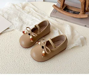 Detail of baby Mary Jane shoes in brown with bow and bead accents on woven background