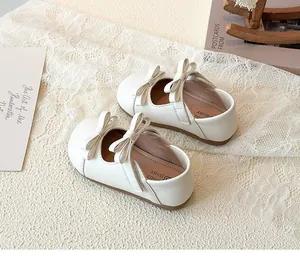 Detail of cream girls Mary Jane shoes with double bow and velcro strap on lace background
