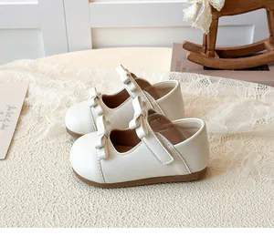 Close-up of cream Mary Jane shoes with dual bows and velcro straps for girls