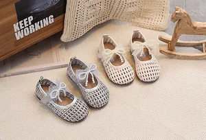 Dettaglio di scarpe Mary Jane intrecciate con fiocchi di pizzo e perle in argento e beige