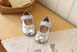 Detailed close-up of shiny silver girl's Mary Jane shoes with bow and lace details