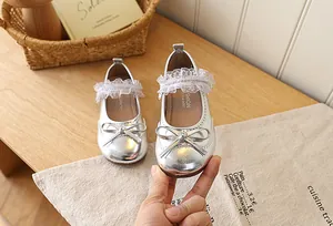 Detailed view of silver Mary Jane girl shoes with bow accent and white lace trim
