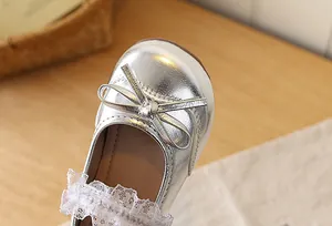 Close-up of silver girls' Mary Janes featuring delicate lace trim and a cute bow detail