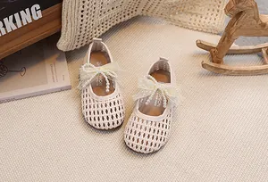 Dettaglio di scarpe da principessa intrecciate da bambina con fiocco e perla