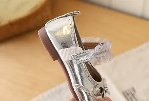Detailed macro shot of silver Mary Jane shoes with delicate lace trim and bow accent