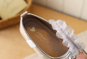 Macro detail of silver Mary Jane shoes featuring delicate white lace and gold interior print