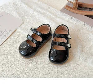 Détail de babies en cuir verni noir avec doubles brides et boucles en perles
