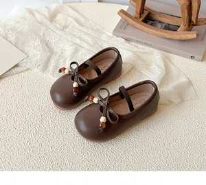 Detail shot of brown matte leather Mary Jane shoes with beaded bow and elastic strap
