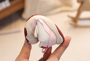 Detailed shot showing the flexible pink baby walking shoe with a non-slip red rubber sole