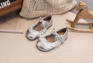 Silberne Baby-Prinzessinenschuhe mit weißer Spitze und Schleifenschnalle auf Webteppich