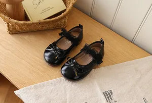 Close-up of black patent leather Mary Jane shoes with bow and lace strap detail