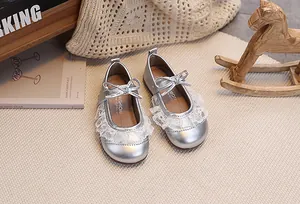 Detailansicht silberner Baby-Mary-Janes mit zarter weißer Spitze und einer metallischen Schleife