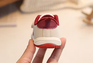 Detail of baby walking shoes featuring soft red non-slip soles and a convenient heel pull tab