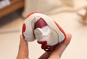 Close-up of flexible red rubber sole on toddler sneakers showing soft and bendable texture