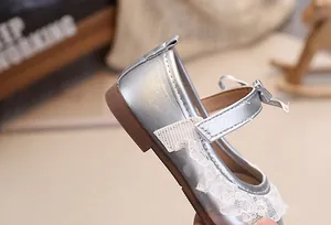 Detailaufnahme silberner Baby-Mary-Janes mit weißer Spitze und Schleifenverzierung