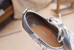 Nahaufnahme von Babyschuhen mit eleganten weißen Spitze und silbernen Schleifen