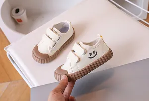 Detail of kids canvas shoes showing velcro straps and rubber toe cap with smiley face logo