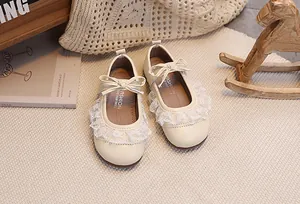 Nahaufnahme beiger Baby-Mary-Janes für Mädchen mit Spitzenbesatz und kleiner Lederschleife