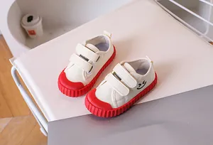 Detail of kids canvas shoe with red rubber sole, smiley face print and velcro straps