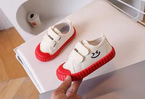 Detail of kids canvas shoe with double velcro straps and a red non-slip rubber sole