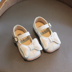 Weiße Mädchen Prinzessinnen Schuhe mit Schleife und Goldene Schnalle auf Ledergrund
