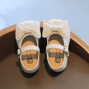 Nahaufnahme weißer Mädchen-Mary-Janes aus Leder mit großer Schleife und Metallschnallendetail