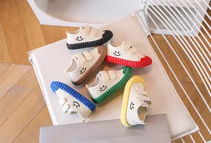 Detail view of colorful children's canvas shoes with smiley faces and ripple rubber soles