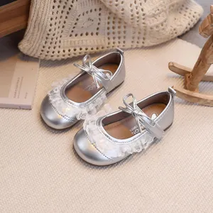 Silberne Baby-Mary-Janes mit Spitzenbesatz und Schleifendetail auf weichem Hintergrund